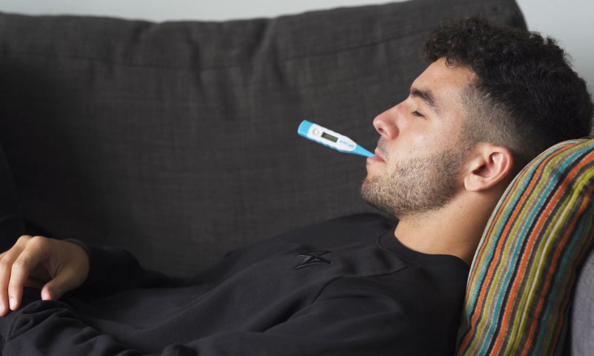 bolestan momak leži na krevetu sa toplomerom u ustima